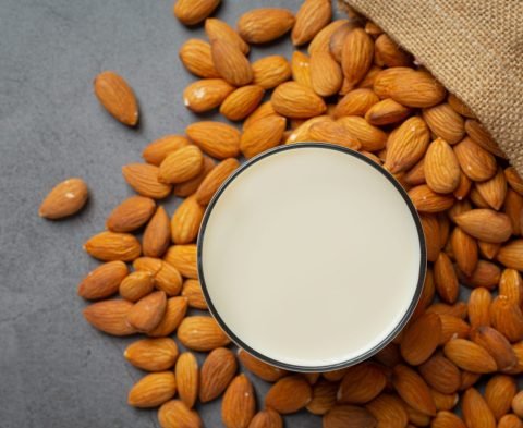 Almond milk with almond on dark background